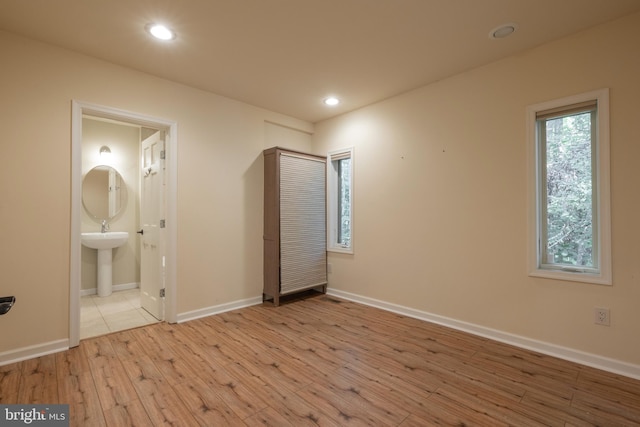 unfurnished bedroom with ensuite bath, light hardwood / wood-style floors, and sink