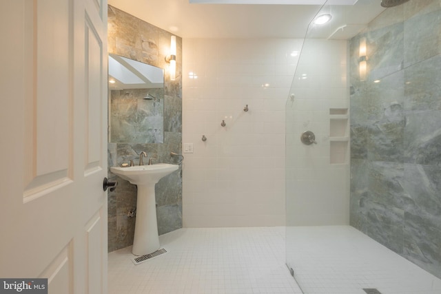 bathroom featuring a tile shower, tile walls, tile patterned floors, and sink