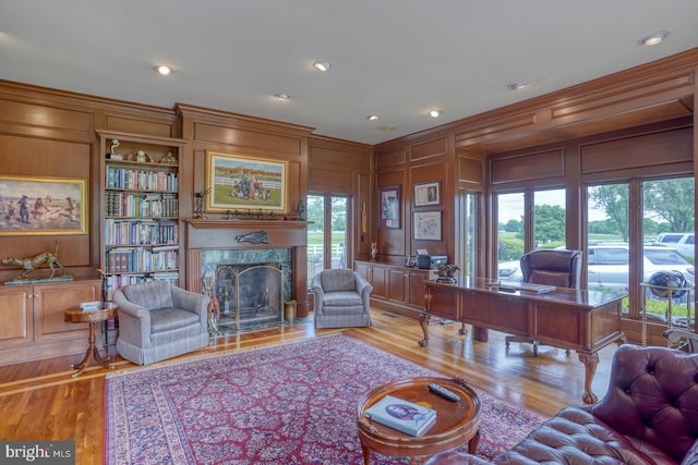 home office with ornamental molding, wooden walls, a fireplace, and light hardwood / wood-style flooring