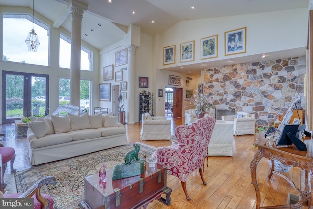 living room featuring decorative columns, high vaulted ceiling, french doors, and light hardwood / wood-style floors