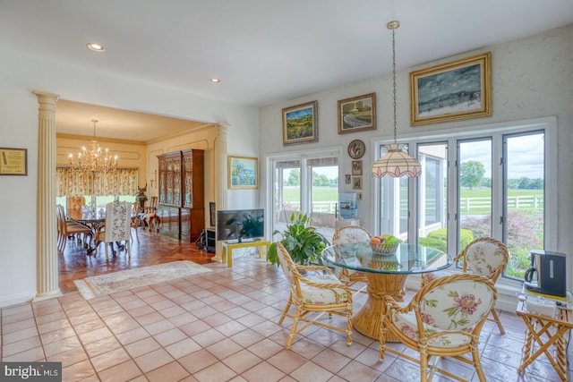 tiled dining area with ornate columns, a healthy amount of sunlight, crown molding, and a chandelier