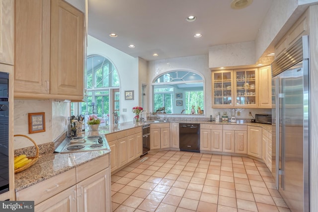 kitchen featuring light brown cabinetry, stainless steel appliances, light stone counters, and light tile patterned floors