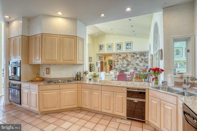 kitchen with lofted ceiling, stainless steel appliances, sink, light tile patterned flooring, and light brown cabinetry