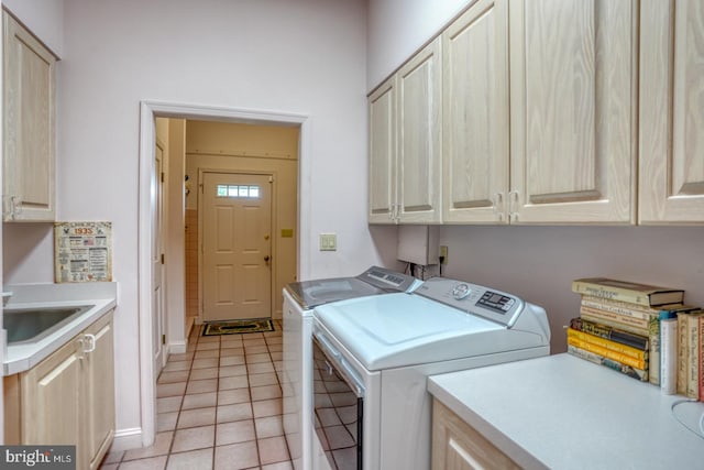 washroom with washing machine and clothes dryer, sink, light tile patterned floors, and cabinets