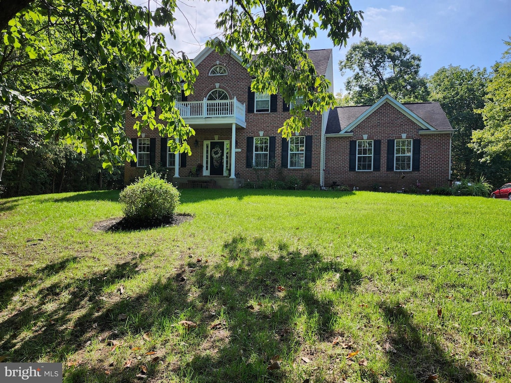 view of front of house with a front yard and a balcony