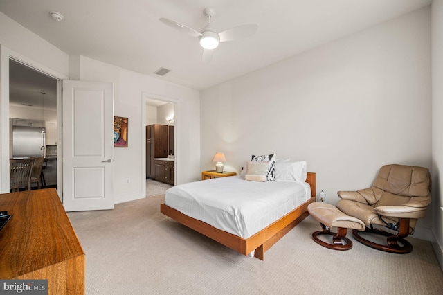 bedroom with ceiling fan, light colored carpet, and ensuite bath