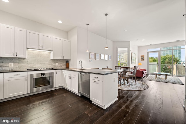 kitchen featuring hanging light fixtures, stainless steel appliances, dark hardwood / wood-style flooring, kitchen peninsula, and white cabinets