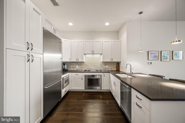 kitchen with appliances with stainless steel finishes, decorative light fixtures, white cabinetry, and sink