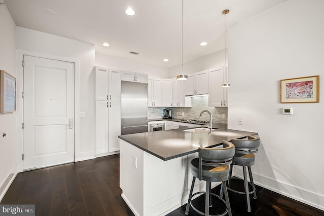 kitchen featuring white cabinetry, kitchen peninsula, built in refrigerator, and hanging light fixtures