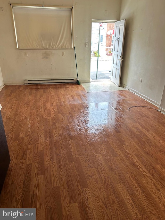 unfurnished room featuring a baseboard heating unit and hardwood / wood-style flooring