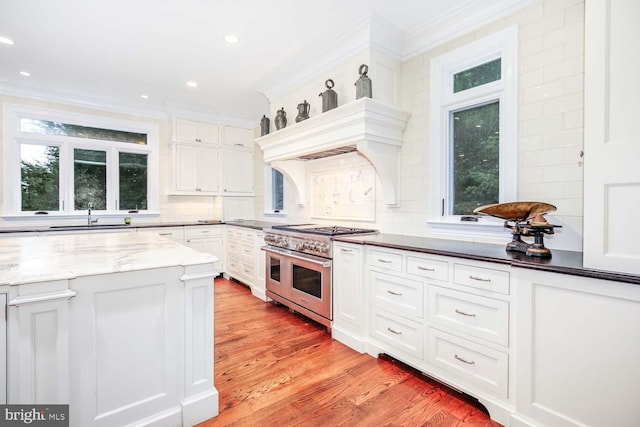 kitchen featuring ornamental molding, light hardwood / wood-style flooring, white cabinetry, and double oven range