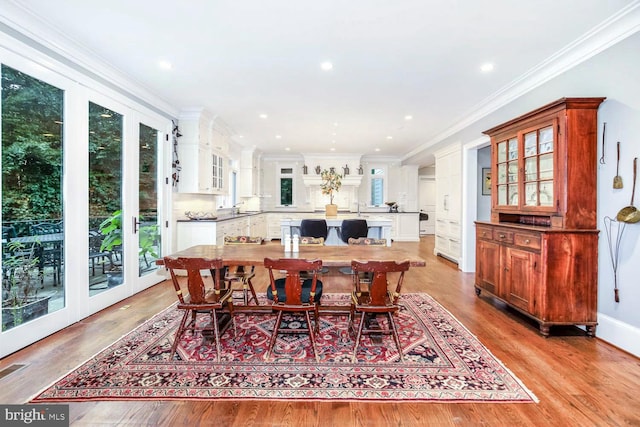 dining area featuring sink, ornamental molding, a wealth of natural light, and light wood-type flooring