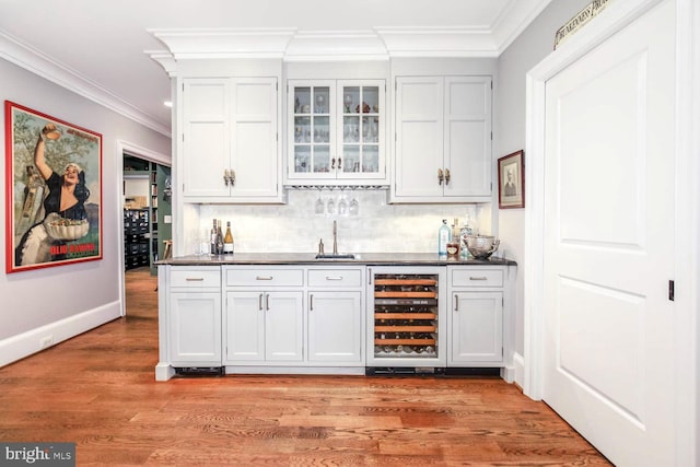 bar with white cabinets, light wood-type flooring, and beverage cooler