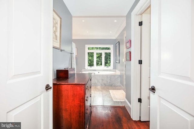 bathroom featuring vanity, hardwood / wood-style flooring, a relaxing tiled tub, and crown molding