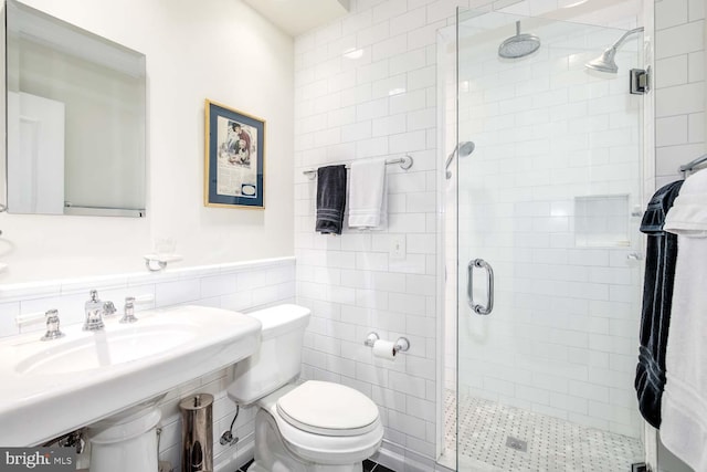 bathroom with a shower with door, tile walls, and toilet