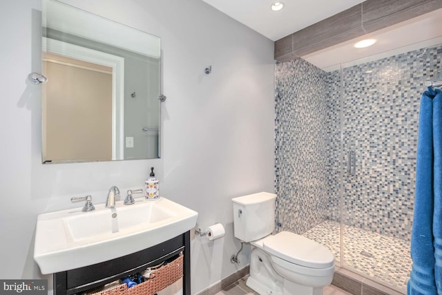 bathroom featuring vanity, a shower with shower door, and toilet