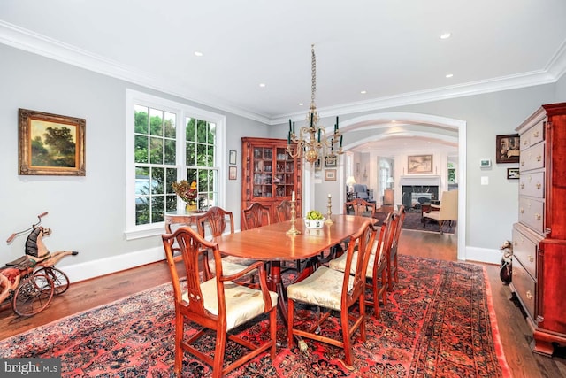 dining area with ornamental molding, a wealth of natural light, an inviting chandelier, and dark hardwood / wood-style flooring