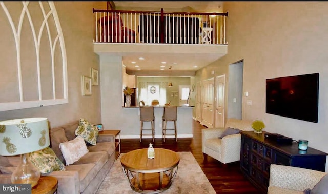 living room featuring a towering ceiling and dark hardwood / wood-style flooring