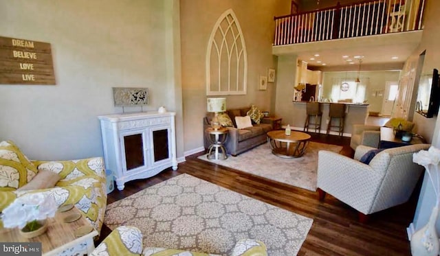 living room featuring a towering ceiling and dark wood-type flooring