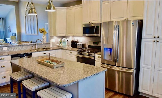 kitchen featuring appliances with stainless steel finishes, light stone countertops, sink, and a kitchen breakfast bar