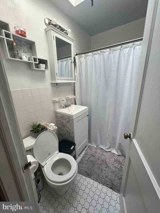 bathroom featuring tile patterned flooring, toilet, curtained shower, tile walls, and vanity