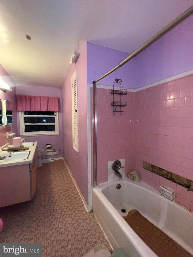 full bathroom featuring tiled shower / bath combo, vanity, and toilet