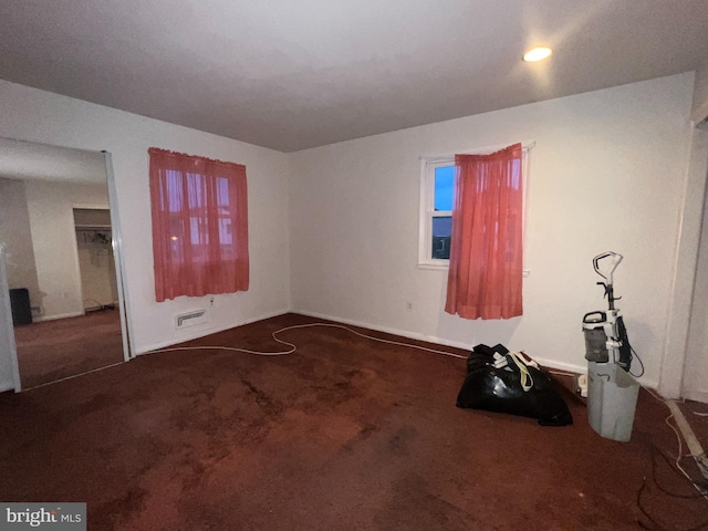 unfurnished room featuring dark colored carpet