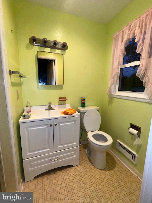 bathroom featuring a baseboard heating unit, vanity, and toilet