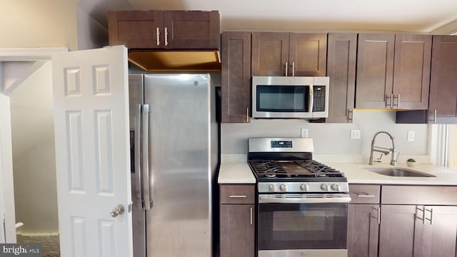 kitchen with appliances with stainless steel finishes, sink, and dark brown cabinetry