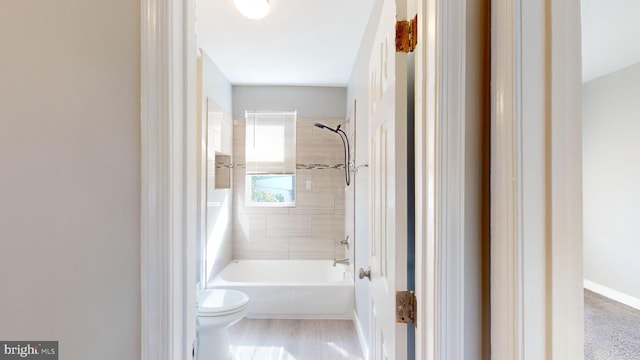 bathroom featuring toilet and tiled shower / bath combo