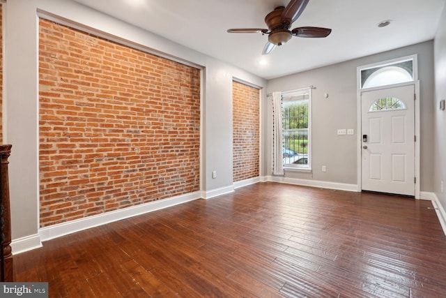 entrance foyer with ceiling fan, brick wall, and dark hardwood / wood-style flooring