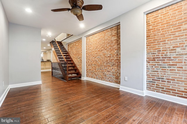 unfurnished room featuring ceiling fan, brick wall, and dark hardwood / wood-style flooring