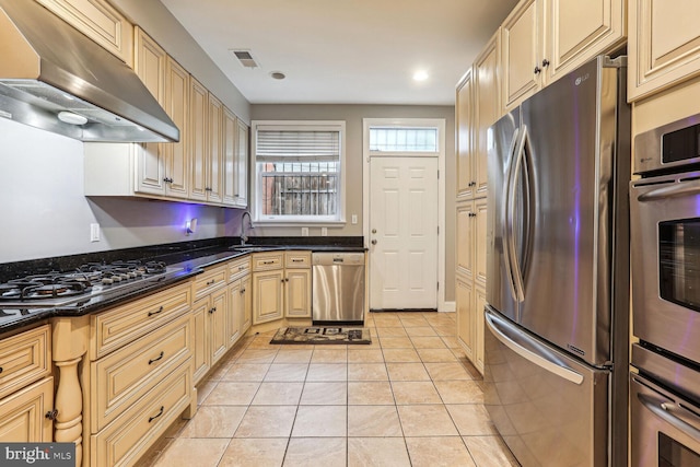 kitchen featuring dark stone counters, sink, ventilation hood, stainless steel appliances, and light tile patterned floors