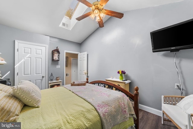 bedroom with lofted ceiling with skylight, dark hardwood / wood-style floors, and ceiling fan