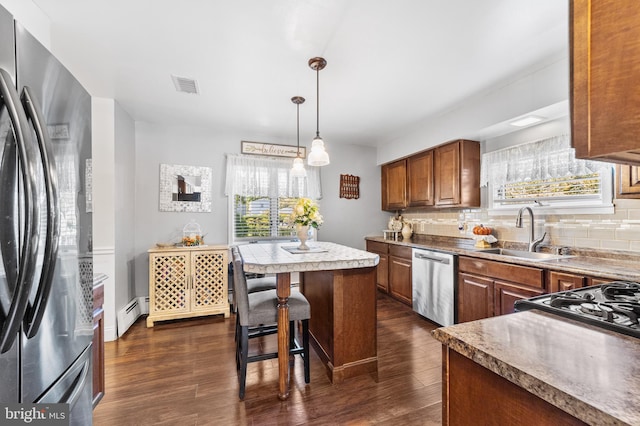 kitchen featuring a baseboard heating unit, dark hardwood / wood-style floors, sink, decorative backsplash, and appliances with stainless steel finishes