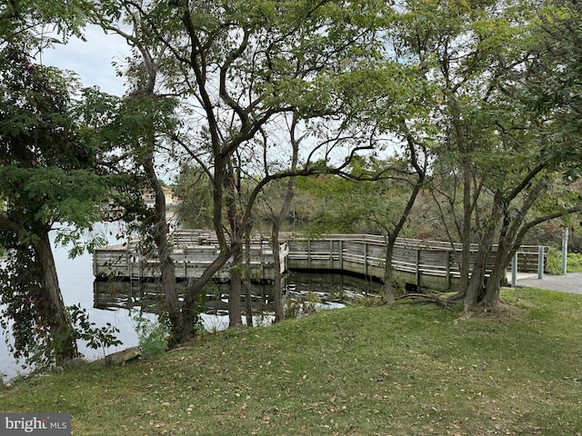 view of dock featuring a lawn and a water view