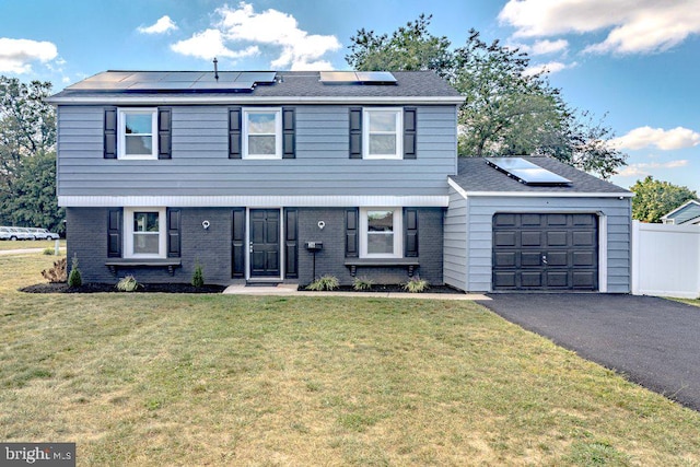 view of property featuring a front yard, a garage, and solar panels