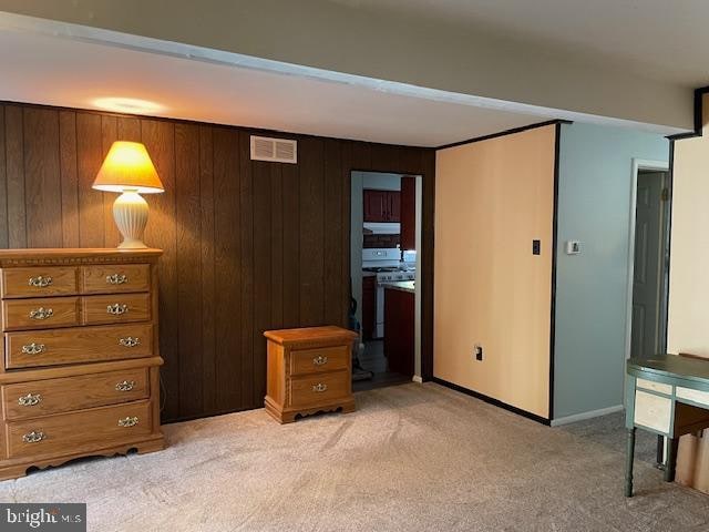 bedroom featuring wood walls and light colored carpet