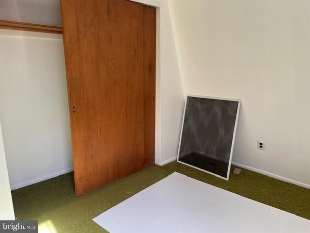 unfurnished bedroom featuring dark colored carpet and a closet