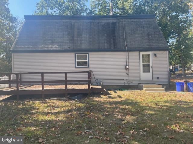 back of property featuring a wooden deck and a yard