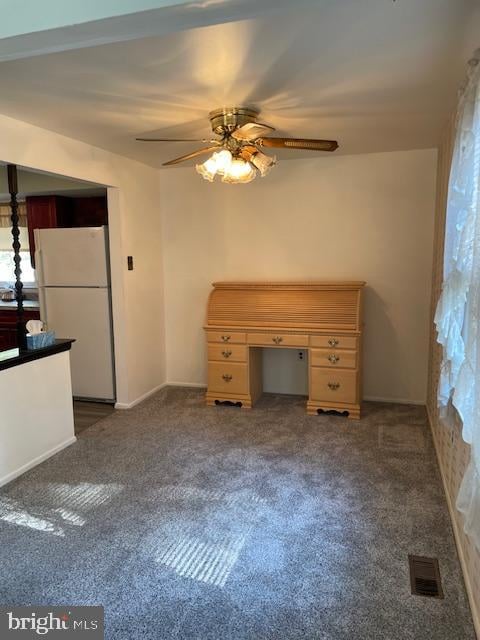 interior space with ceiling fan and dark carpet