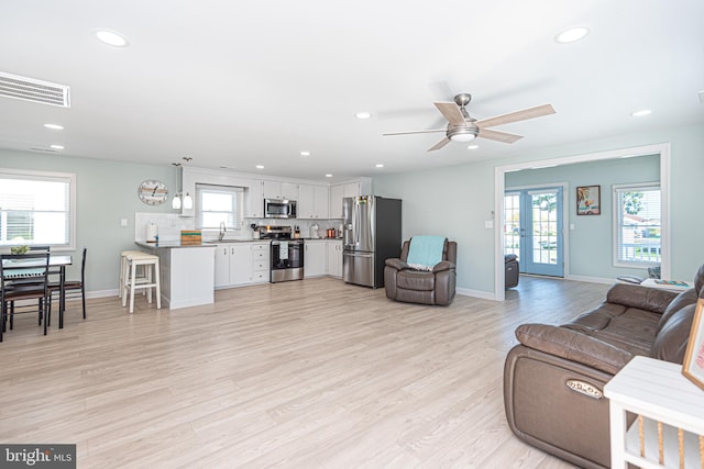 living room featuring ceiling fan, light hardwood / wood-style flooring, and sink