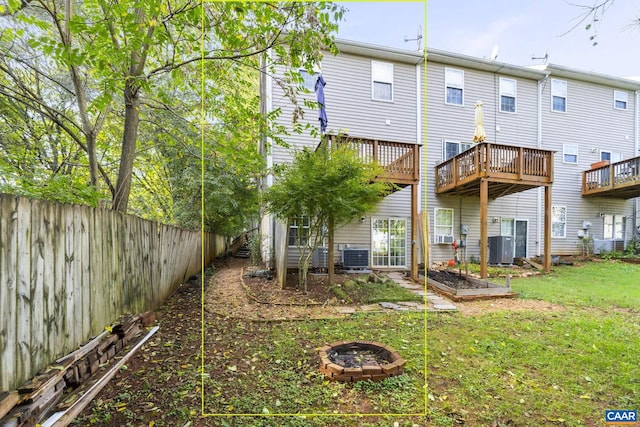 back of house featuring a lawn, central AC unit, a deck, and a fire pit