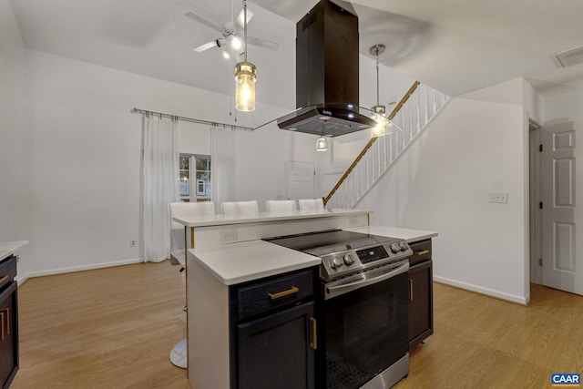 kitchen with light hardwood / wood-style flooring, island exhaust hood, stainless steel electric stove, and a kitchen island