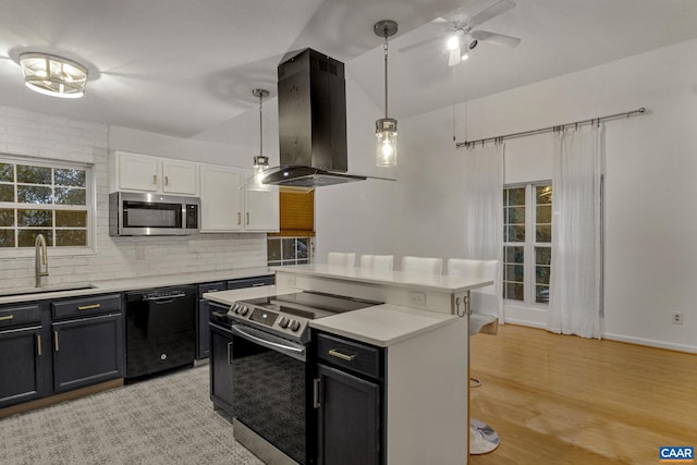 kitchen featuring island range hood, decorative light fixtures, light hardwood / wood-style flooring, white cabinetry, and appliances with stainless steel finishes