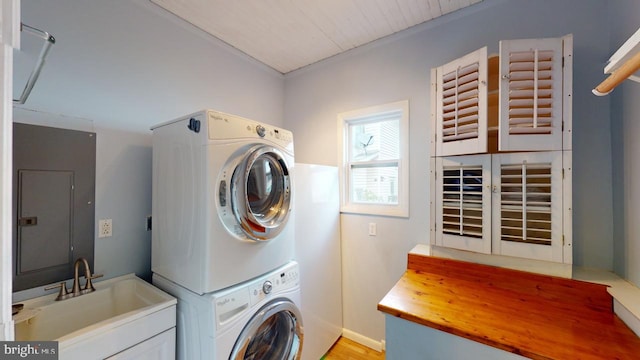 laundry area featuring laundry area, a sink, stacked washing maching and dryer, light wood-type flooring, and electric panel