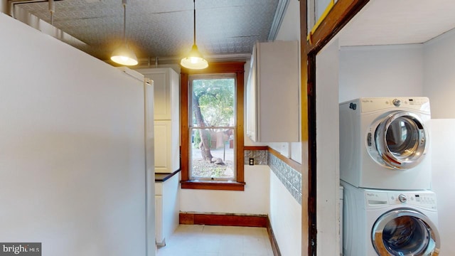 laundry room featuring baseboards, laundry area, and stacked washer / dryer