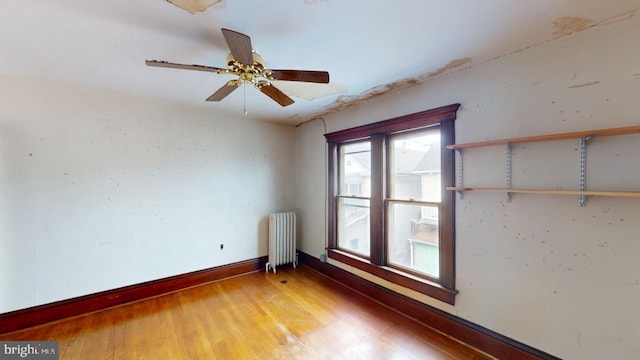 empty room featuring ceiling fan, wood-type flooring, and radiator