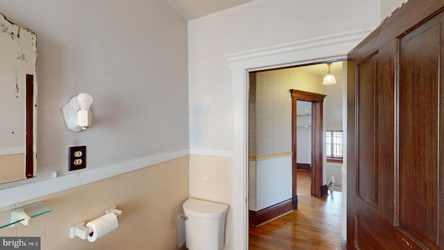 bathroom with wood finished floors, a wainscoted wall, and toilet