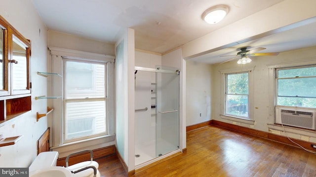 full bathroom featuring a stall shower, a ceiling fan, wood finished floors, and cooling unit